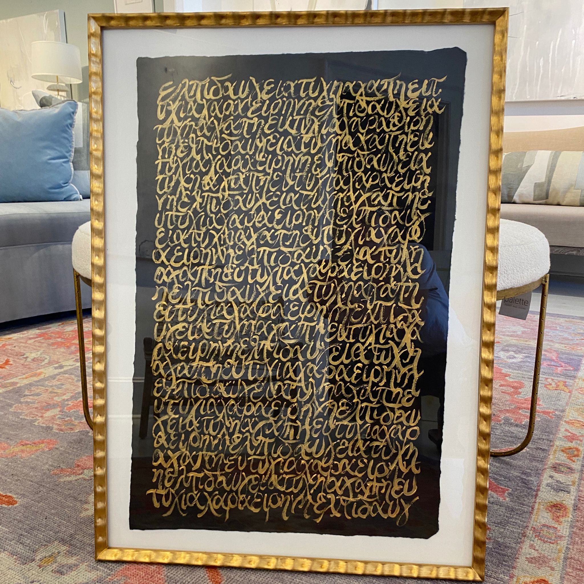 Framed artwork with gold text on a black background in a living room setting.
