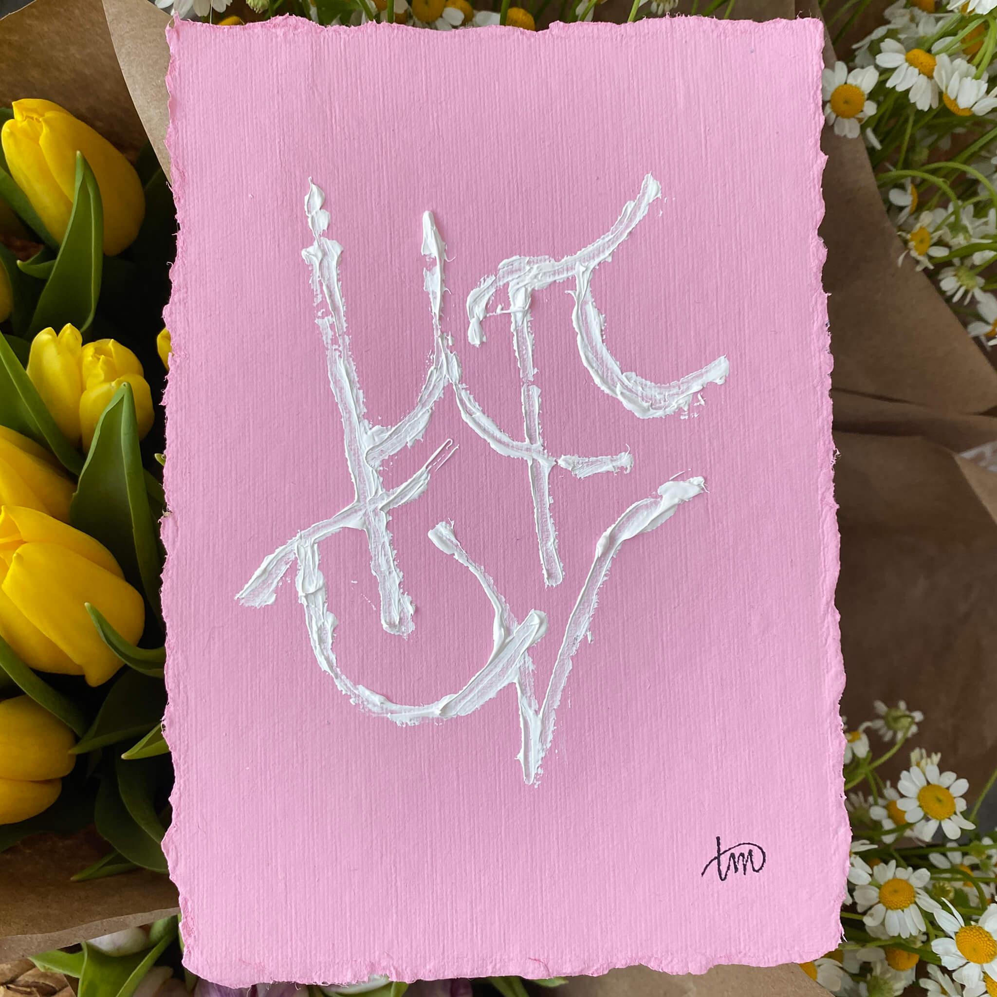 Custom Grammata painting by Richmond artist Theodora Miller on pink handmade cotton rag paper with deckled edges, featuring intertwined Greek initials in textured white paint.